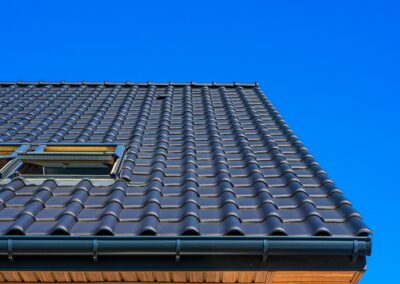 Vertical low angle closeup shot of the black roof of a building with a blue background